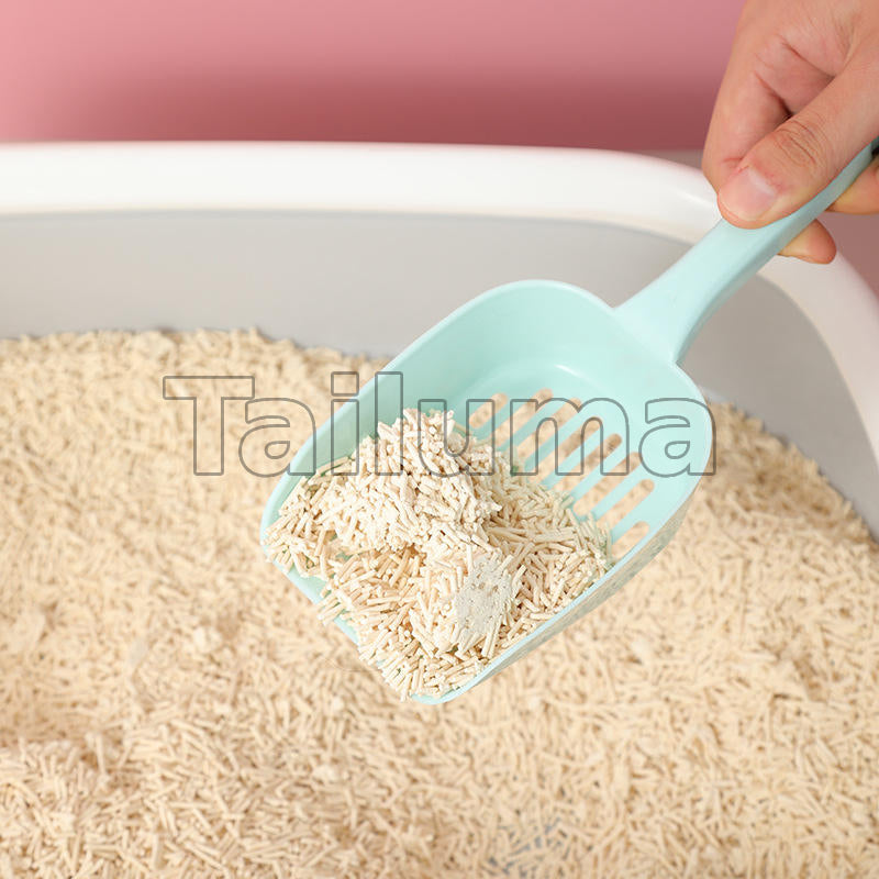 A hand using a plastic scoop to lift cat litter from a litter box.